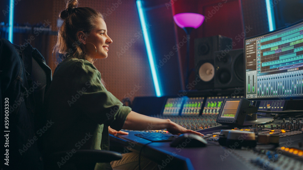 Beautiful, Stylish Female Audio Engineer and Producer Working in Music Recording Studio, Uses Mixing Board and Software to Create Cool Song. Creative Girl Artist Musician Working to Produce New Song