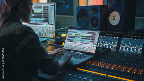 фотографія Modern Music Record Studio Control Desk with Laptop Screen Showing User Interface of Digital Audio Workstation Software