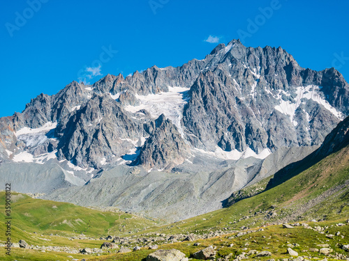 Mountain landscape on the french Alps, Massif des Ecrins. Scenic rocky mountains at high altitude with glacier, green meadows and hiking paths for tourism summer vacation