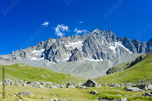 Mountain landscape on the french Alps, Massif des Ecrins. Scenic rocky mountains at high altitude with glacier, green meadows and hiking paths for tourism summer vacation