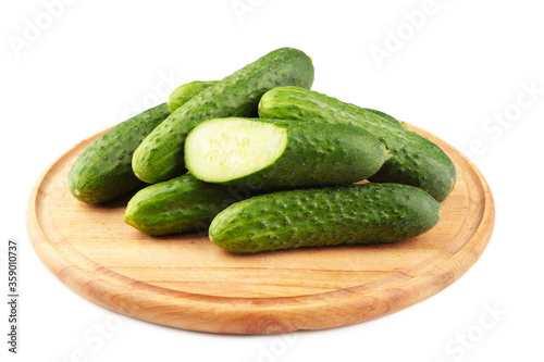 Fresh cucumbers on a wooden cutting board isolated on white background