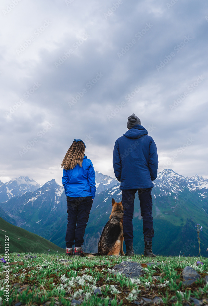 A girl and man travelers with a dog stay in the mountains, Georgia, Svaneti