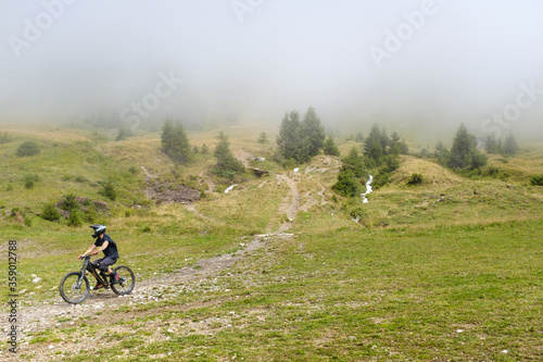 Vászonkép Mountainbike descending out of the fog