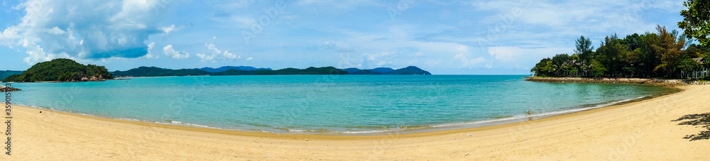 Panoramic shot of a beautiful golden sand beach with blue water beautiful fluffy clouds shot in Malaysia