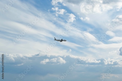Beautiful white clouds on azure blue sky and small silhouette of an airplane in the distance. Travel and transportation concept.