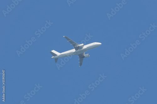 Airplane flying in the sky. Commercial passenger jet airliner in flight after take off from the airport. Bright blue sky background. Transportation and business travel tourism concept.