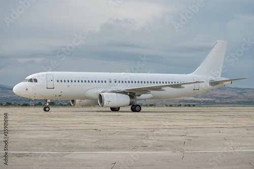 Side view of airplane. White commercial passenger jet airliner on airport apron. Cloudy sky background. Modern technology in fast transportation, business travel aviation, tourism charter flights.