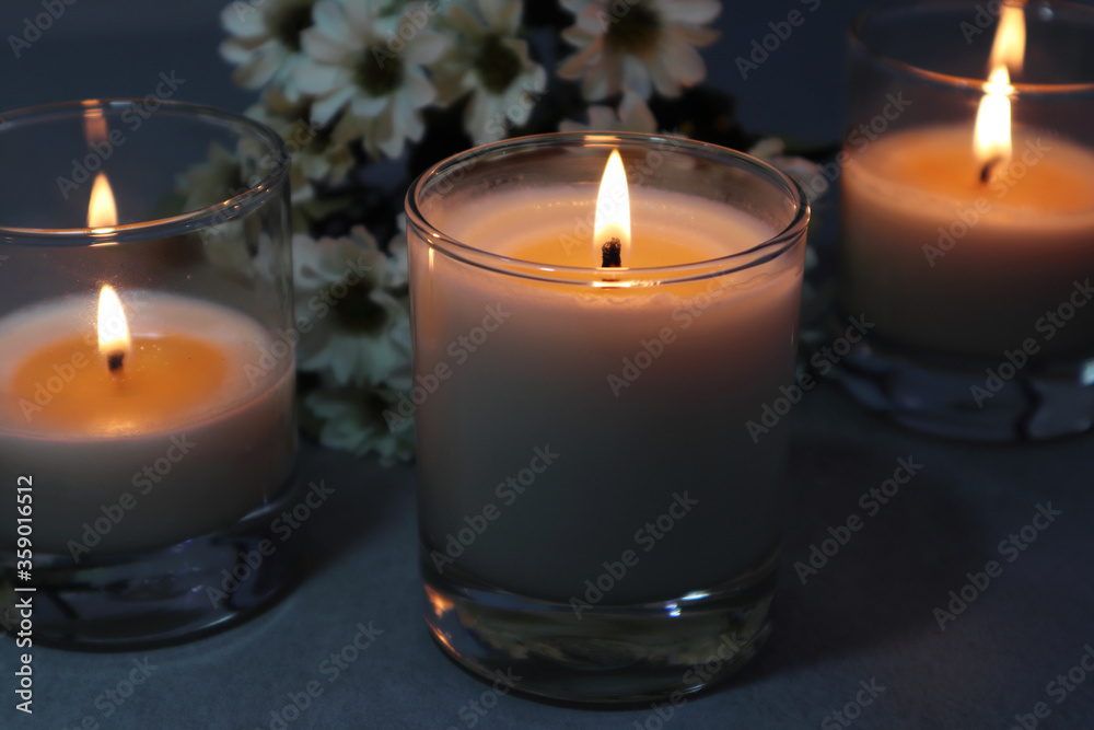 lighting aroma scented candles are on the grey table with a big leaf in the bedroom