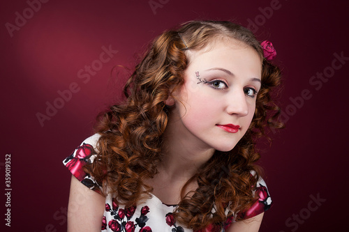 Portrait of a cute girl in pin-up style on red paper background. Stylish photography in vintage style.