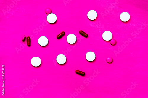 white tablets on pink background. top view