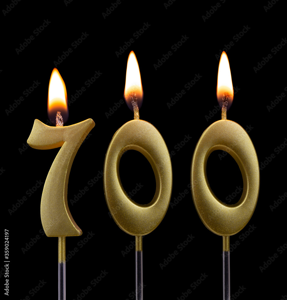 Golden birthday candle isolated on black background, number 700 Golden birthday candle isolated on black background, number 700