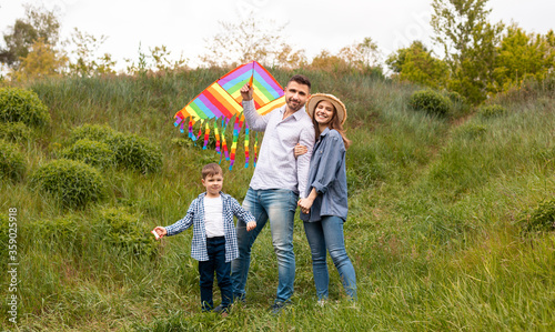 Portrait of happy family with bright kite in countryside