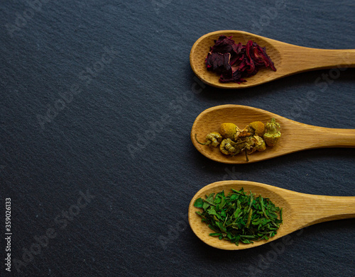 Spices background on wooden spoons. Parsley, chamomile, hibiscus