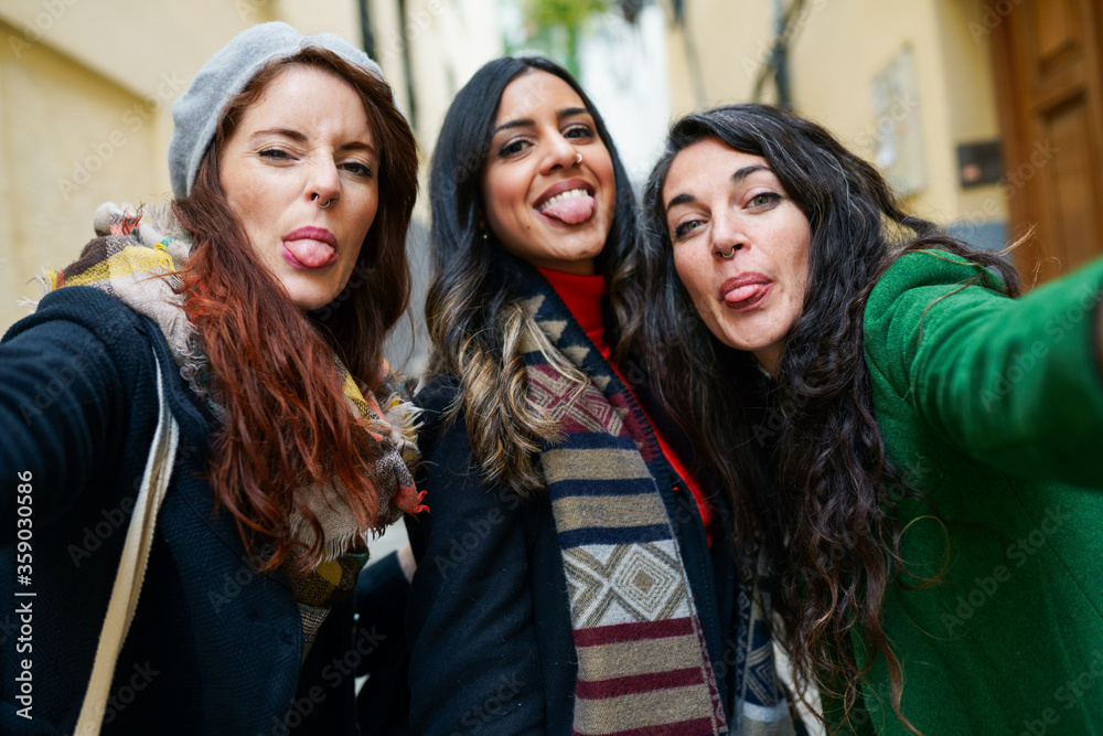Fototapeta premium Group of woman taking a selfie photo sticking out their tongues
