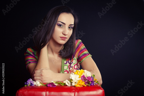 Young woman brunette in a bright dress posing in Studio on black background. Glamur and fashion.