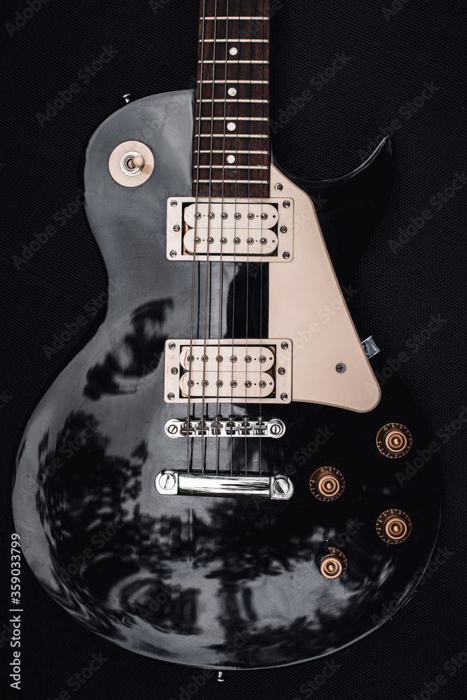 Black and white electric bass guitar. Musical instrument close-up. Stylish still life with parts of the guitar. Vulture, deck and strings. Fine tuning the bass instrument Black and white electric bass guitar. Musical instrument close-up. Stylish still life with parts of the guitar. Vulture, deck and strings. Fine tuning the bass instrument