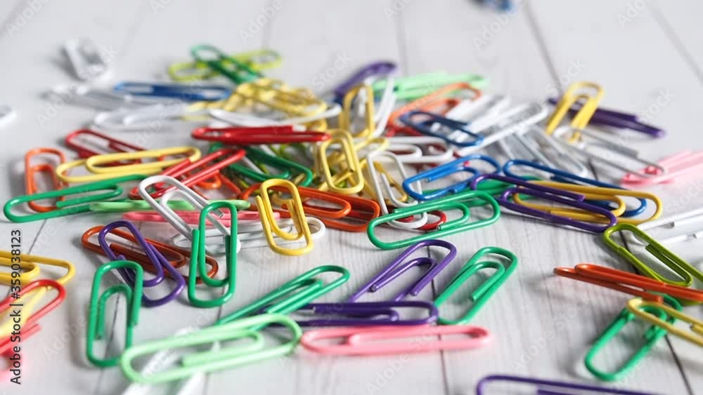 Colored paper clips fall on the surface of the white desktop. Close up, concept of work or study. Colored paper clips fall on the surface of the white desktop. Close up, concept of work or study.