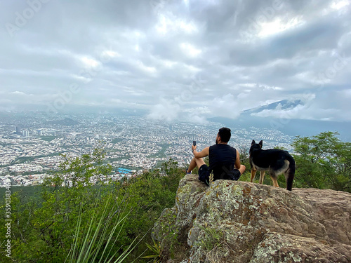 Young man enjoying the view of the city of Monterrey with his dog