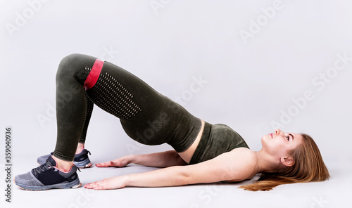 Young sportive woman doing a glute bridge isolated on gray background photo