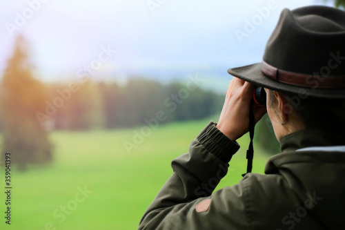 Photography Hunter woman with  binoculars  looking  wild animals in the green country