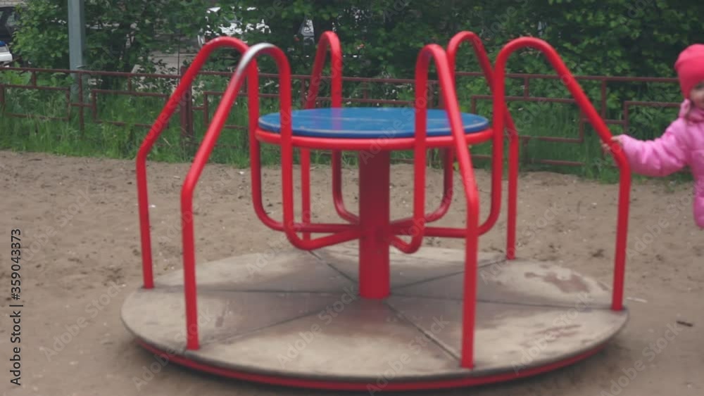 The girl runs around the carousel and spins. Russian playground The girl runs around the carousel and spins. Russian playground
