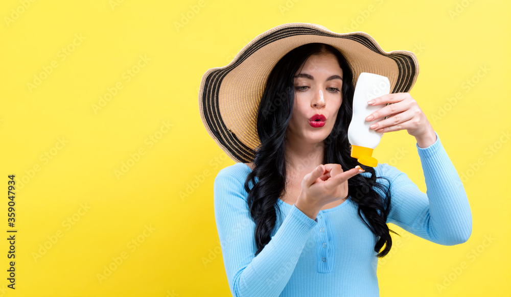 Young woman with sunscreen on a yellow background Young woman with sunscreen on a yellow background