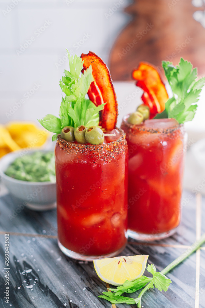 Bloody Mary cocktail with bacon, celery and olives. Chilled brunch and breakfast alcohol drink. Red, green colors. Iced cocktail. Appetizer weekend party. Bloody Mary cocktail with bacon, celery and olives. Chilled brunch and breakfast alcohol drink. Red, green colors. Iced cocktail. Appetizer weekend party.