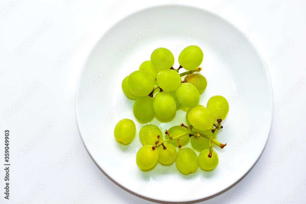 Green delicious ripe grapes on a white plate Green delicious ripe grapes on a white plate
