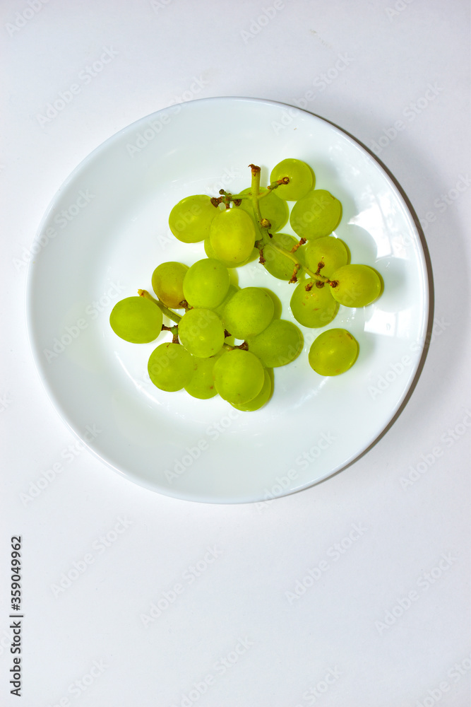 Green delicious ripe grapes on a white plate Green delicious ripe grapes on a white plate