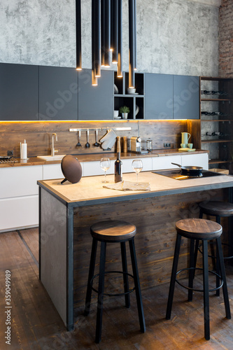 luxury studio apartment with a free layout in a loft style in dark colors. Stylish modern kitchen area with an island, cozy bedroom area with fireplace and personal gym