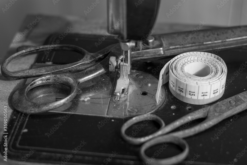 Old vintage sewing machine with an old rusty pair of scissors and a Tape Measure Sewing Tailor Cloth Ruler.Black and white photography.