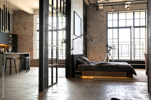 luxury studio apartment with a free layout in a loft style in dark colors. Stylish modern kitchen area with an island, cozy bedroom area with fireplace and personal gym photo