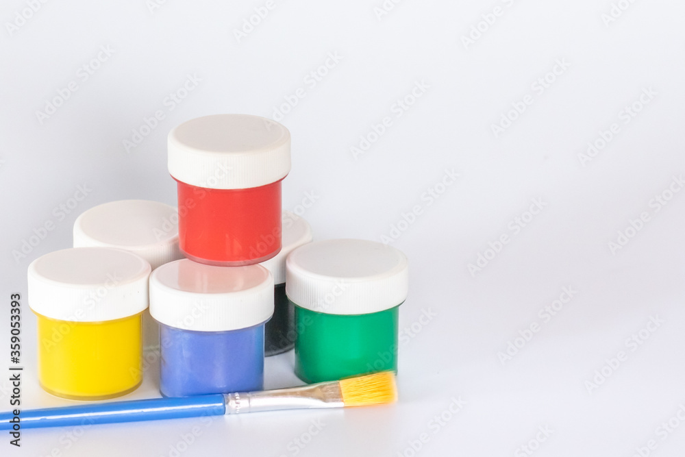 Jars of gouache paints with a brush on a white background. Banner template for children's creativity. Jars of gouache paints with a brush on a white background. Banner template for children's creativity.