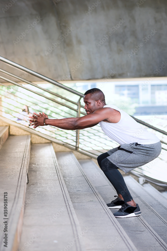 African-American men are exercising outdoors by doing squats. To increase the muscles and strength of the lower part of the body