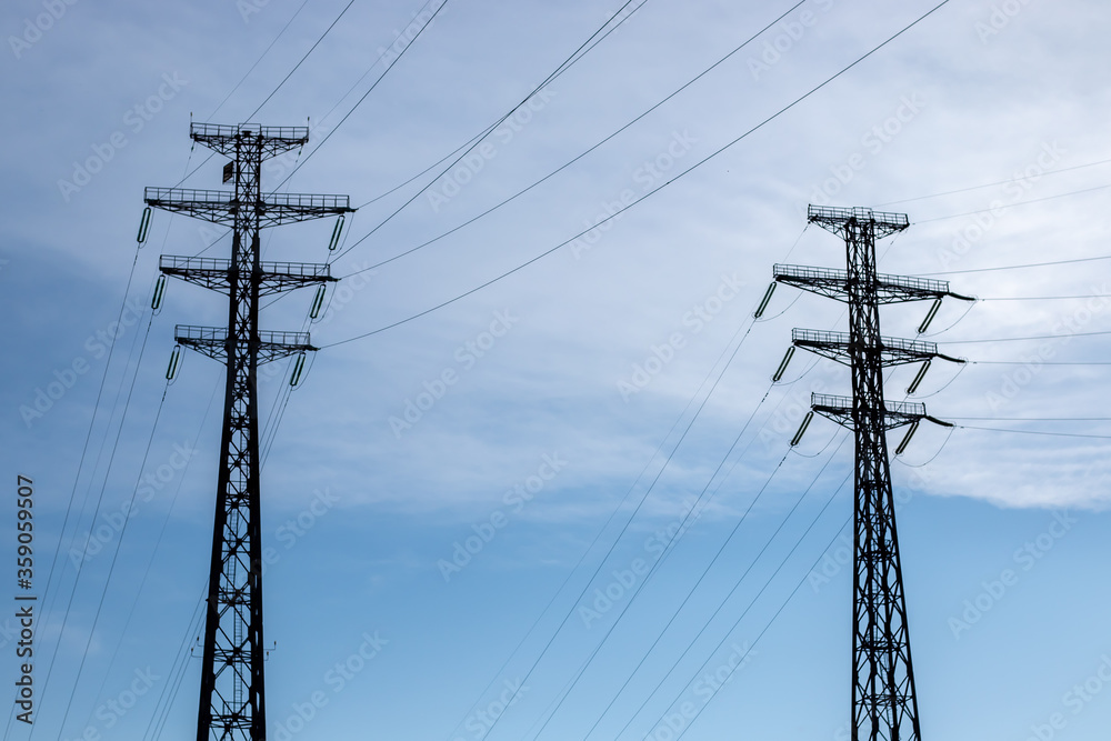 Two towers of power lines on a background of blue sky with clouds. Two towers of power lines on a background of blue sky with clouds.