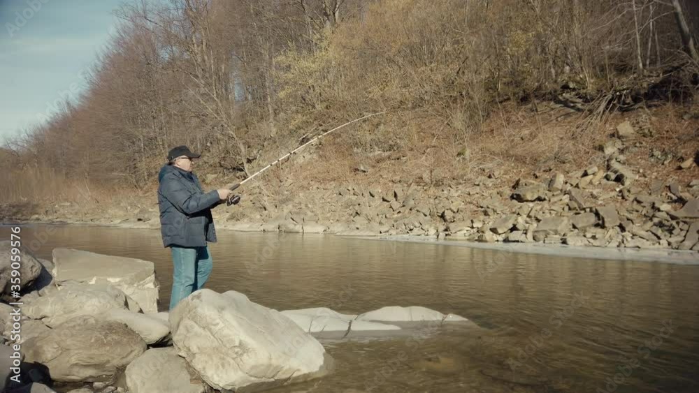 Man pulls fish out of the water.  Male fisherman fishing at the suny day. Outdoor activity