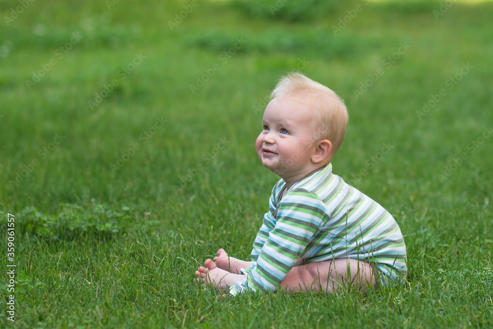 cute little baby sitting on the green grass and looking upwards, banner copy space cute little baby sitting on the green grass and looking upwards, banner copy space