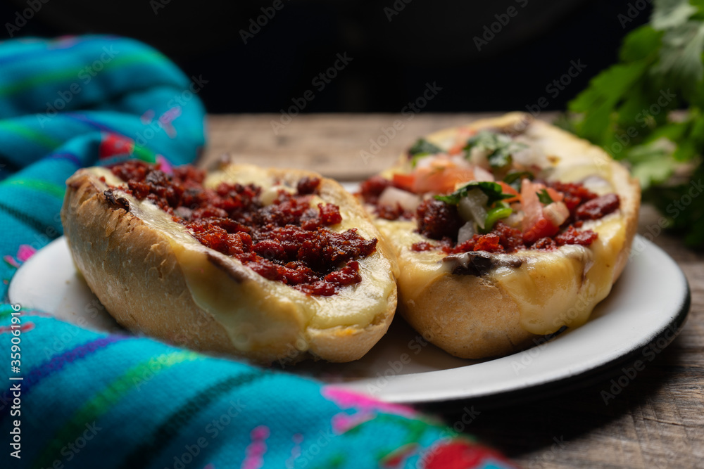 Mexican molletes with chorizo and fresh sauce on wooden background