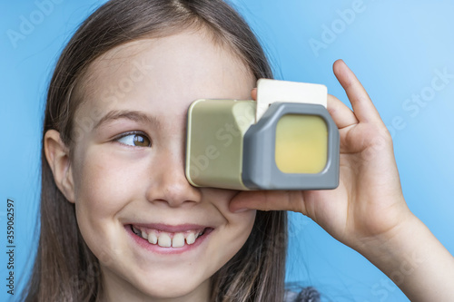 Child girl looks at old photos through a diascope. Banner template on blue background. photo