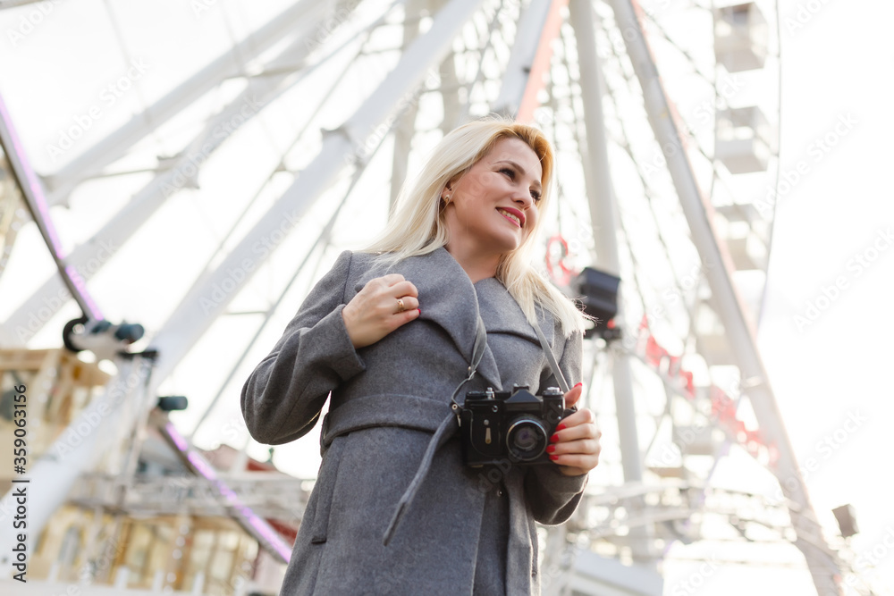 Young woman walking outdoors on the city street near ferris wheel smiling cheerful. Young woman walking outdoors on the city street near ferris wheel smiling cheerful.