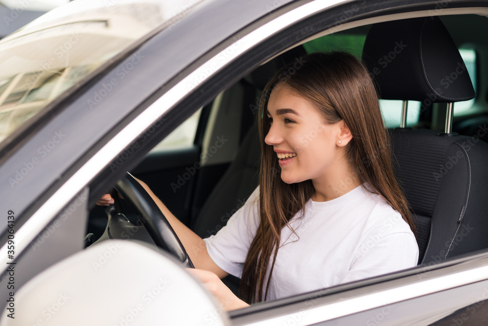 Young beautiful smiling girl driving a car on the road