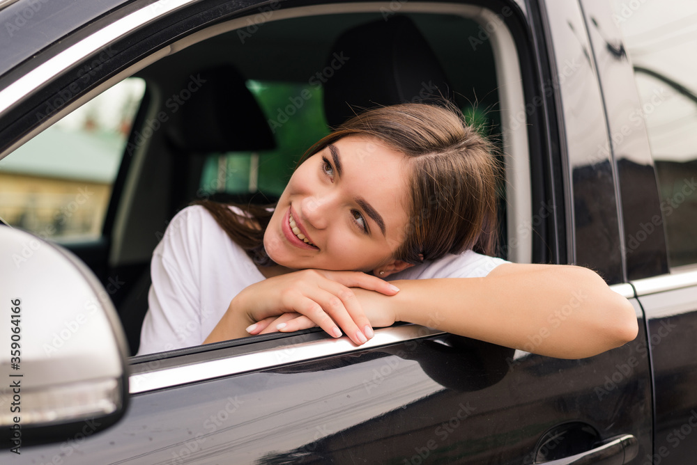 Young woman leaning her elbow over car window while enjoying road trip
