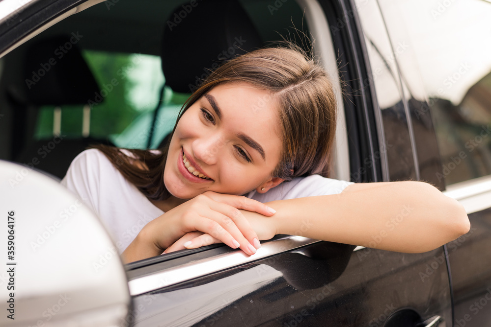 Relaxed happy woman on summer roadtrip travel vacation leaning out car window