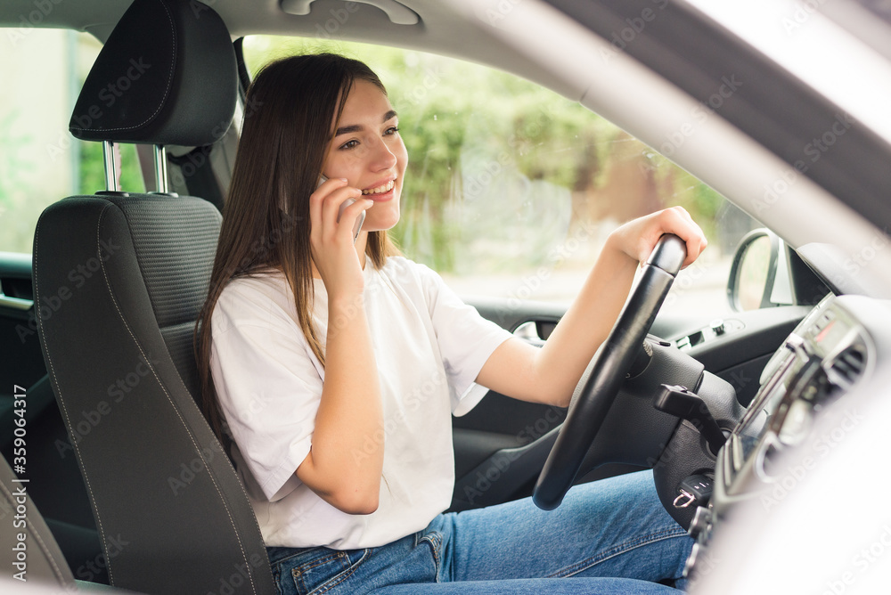 Young woman driving the car and talking on the phone