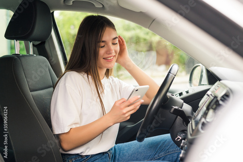 Young woman aending messages from phone while driving © dianagrytsku