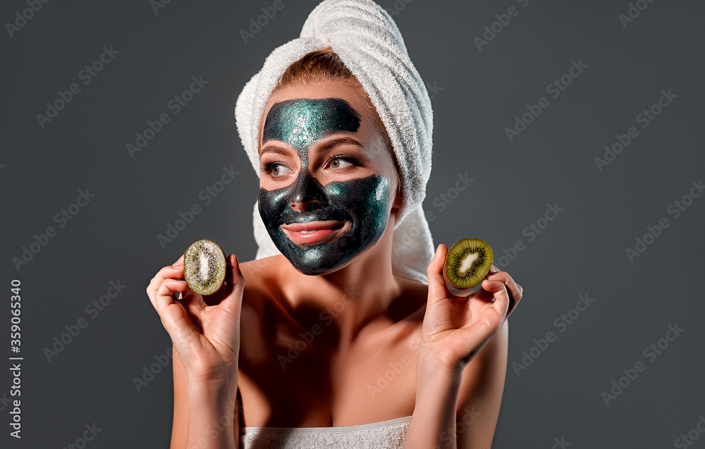 Beautiful woman with green peel-off mask on a gray background.