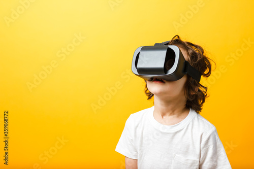 Close-up of little boy in virtual reality headset. Boy wearing virtual reality glasses white tshirt at yellow background