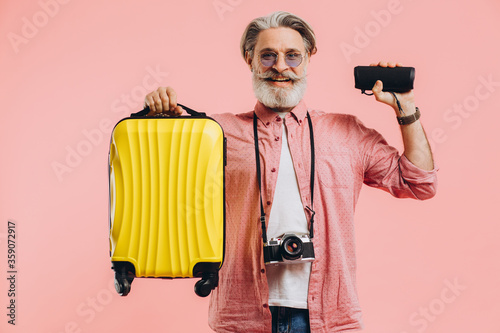 Happy bearded stylish man in sunglasses with camera holding a suitcase and a portable speaker