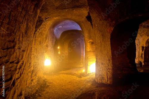 Dark abandoned underground chalky cave temple illuminated by candles