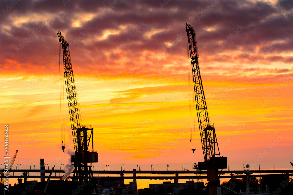 Construction cranes on the Sunset over the sea in Russia